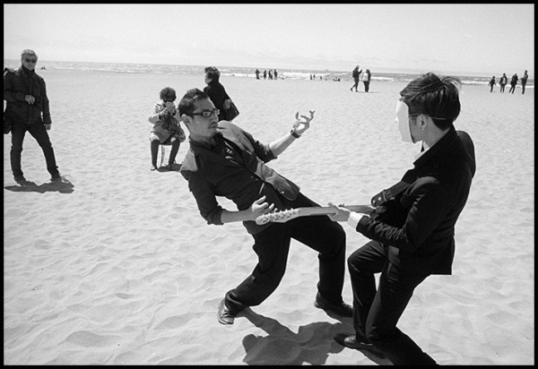 Ocean Beach, San Francisco . A band was playing on sand. A complete set up, with a bandstand, generator, drums, guitars and really bad music. These two guys were carrying on slightly offstage. It seemed like a lesson in how to rock and roll.